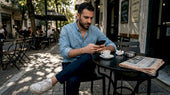 Ένας σύγχρονος άντρας, ντυμένος με στυλ, απολαμβάνει τον καφέ του σε ένα μοντέρνο αστικό καφέ.